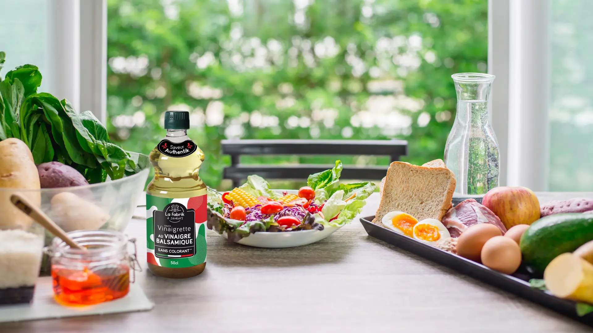 Bouteille de sauce vinaigrette La Fabrik à Saveurs posée sur une table, à côté d'une salade