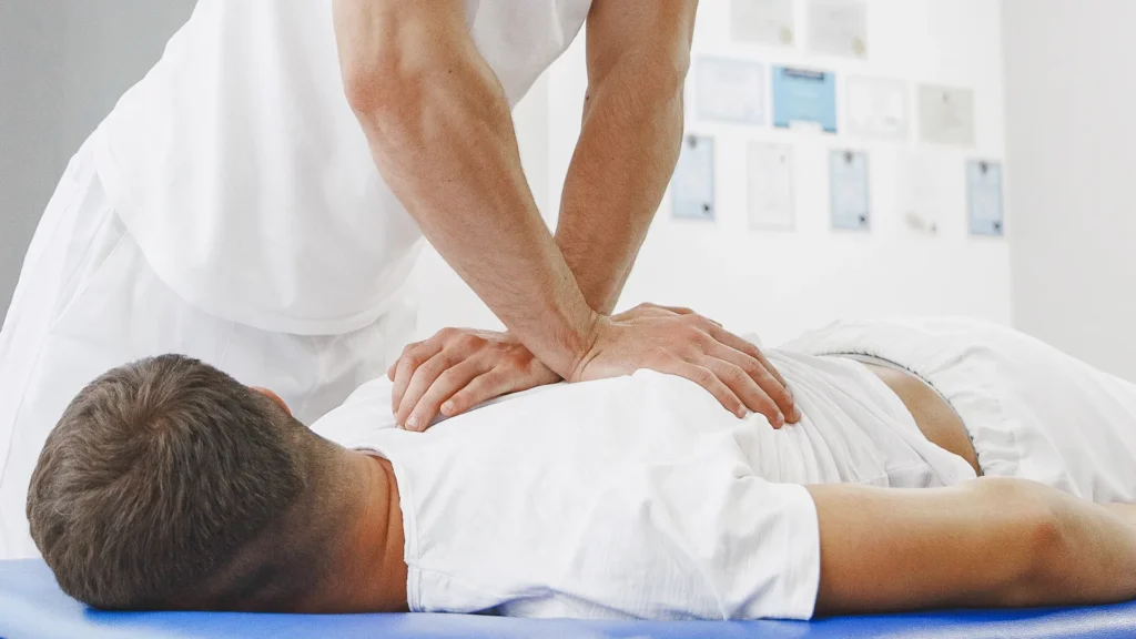 Masseur kinésithérapeute exerce sur le dos d'un patient